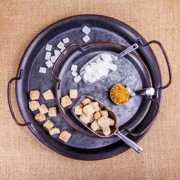 Various types of cane sugar in spoons on vintage metal platter Stock Photos