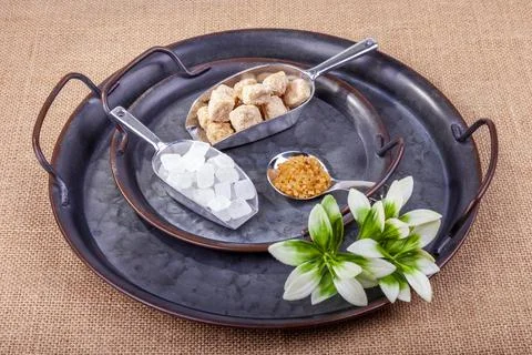 Various types of cane sugar in spoons on vintage metal platter Stock Photos