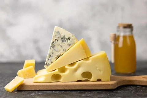 Various types of cheese, blue cheese and brie with honey on a ceramic table. Stock Photos