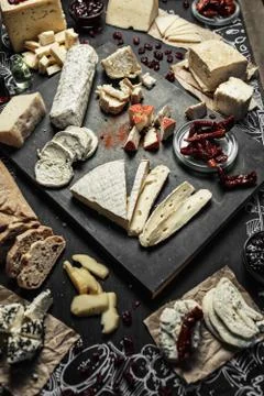 Various types of cheese with different spices, wine glasses and bread slices  Foto stock