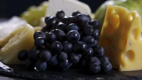 Various types of cheese, including mozzarella, lie next to pears, grapes and Stock Footage 159522661