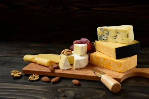 Various types of cheese on a rustic table Stock Photos