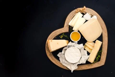 Various types of cheese on a stand in the shape of a heart, concept elegant life Photos