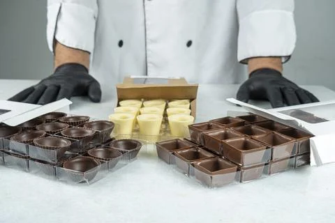Various types of chocolates in different shapes inside boxes and a confecti.. Stock Photos