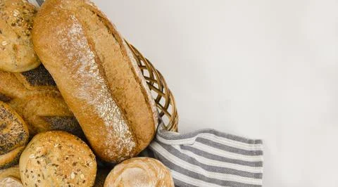 Various types of freshly baked bread and buns in a basket. Stock Photos