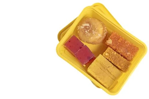 Various types of Indian sweets in a yellow box on a white background. Stock Photos