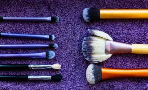 Various types of make-up brushes on purple towel background Stock Photos