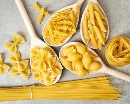 Various types of pasta on grey background, from above Stock Photos