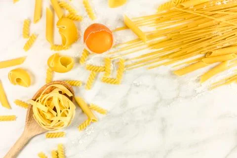 Various types of pasta on marble with egg and copyspace Photos