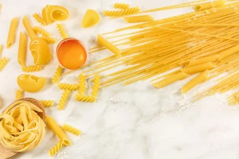 Various types of pasta on marble with egg and copyspace Foto stock