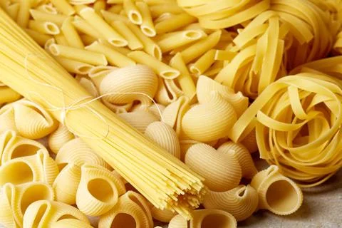 Various types of pasta on stone table Stock Photos