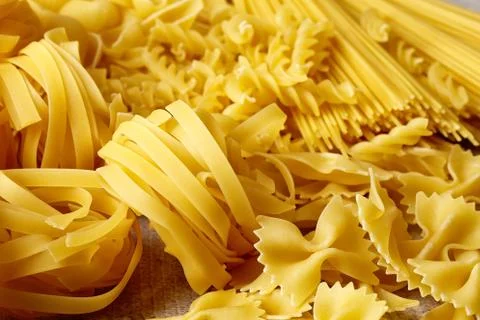 Various types of pasta on stone table Stock Photos
