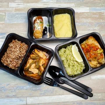 Various types of ready meals in disposable containers on the table Stock Photos