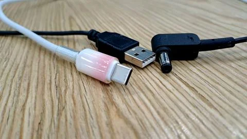 Various USB type-c and power charging cables on wood. Stock Photos