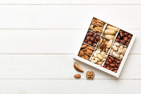 Various varieties of nuts lying in paper box on table background. Top view... Stock Photos