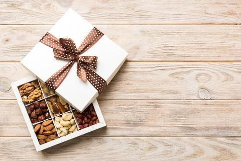 Various varieties of nuts lying in paper box on table background. Top view. H Stock Photos