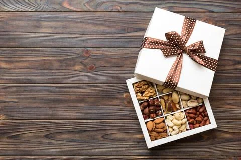 Various varieties of nuts lying in paper box on table background. Top view... Stock Photos