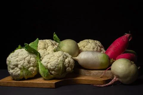 Various vegetables on a black background. Different varieties of radish with cau Stock Photos