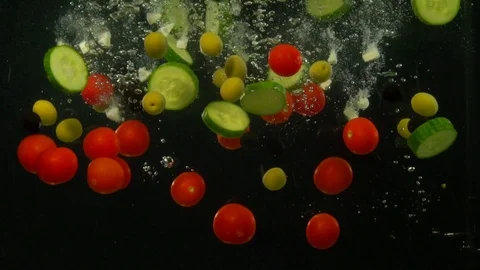 Various vegetables fall into the water creating bubbles. Stock Footage 117108607
