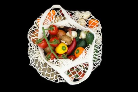 Various vegetables in white mesh net bag and isolated on black background Stock-Fotos