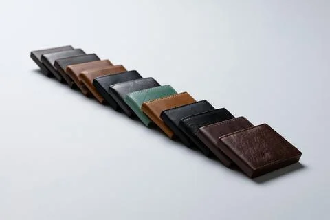 Various wallets arranged in a row on a gray surface with different colors a.. 스톡 사진