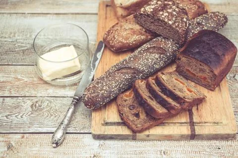 Various of wheat and rye bread on a chopping board. Bread, table knife and Stock Photos