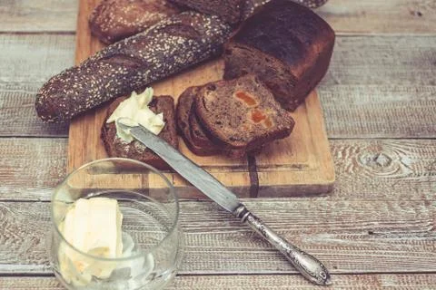 Various of wheat and rye bread on a chopping board. Bread, table knife and Stock Photos