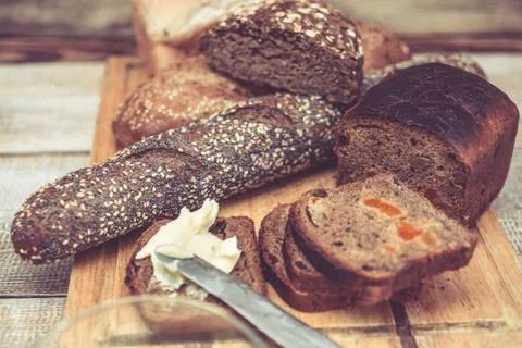 Various of wheat and rye bread on a chopping board. Bread, table knife and Stock Photos