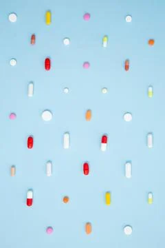 Various white medication tablets and capsules on blue background. Concept of  Stock Photos
