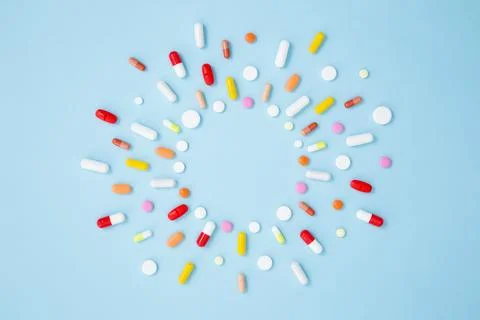 Various white medication tablets and capsules on blue background. Concept of  Stock Photos