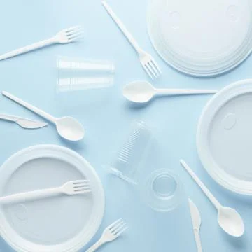 Various white plastic disposable tableware on blue background. Stock Photos