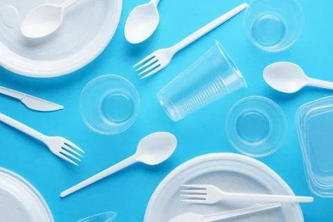 Various white plastic disposable tableware on blue background. Stock Photos