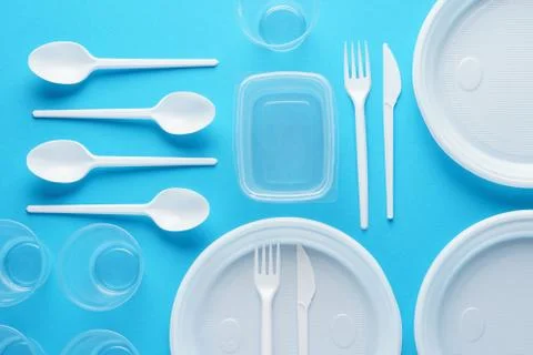 Various white plastic disposable tableware on blue background. Stock Photos