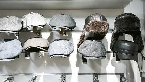 Various winter hats displayed on rack in clothing store. Stock Photos