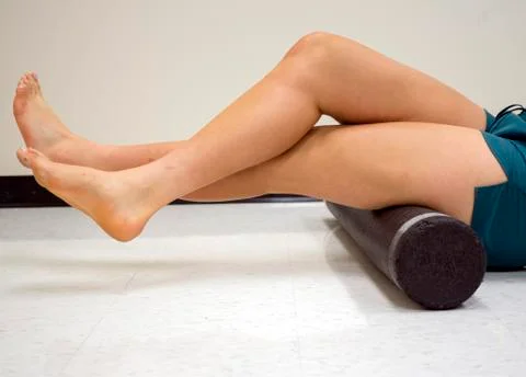Varsity athlete using a foam roller to release her tight muscles Stock Photos