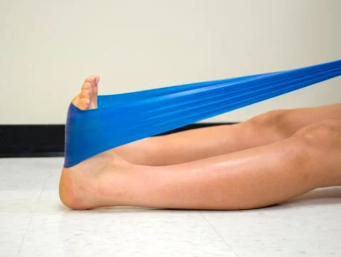 Varsity athlete using a theraband exercise band to strengthen her ankle Stock Photos