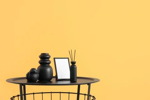 Vase and reed diffuser on coffee table near orange wall in interior of living Stock Photos