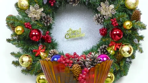 Vase with cones and berries in front of a decorated Christmas wreath Video stock 166343648
