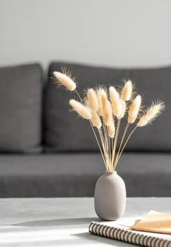 Vase with dried rabbit tail grass  and notebook on gray table in front of d.. Stock Photos