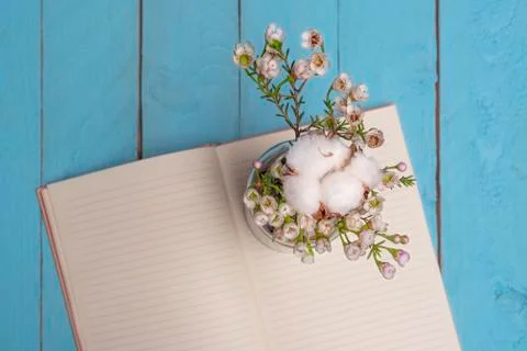 Vase of flowers and open notebook on wooden table Stock Photos