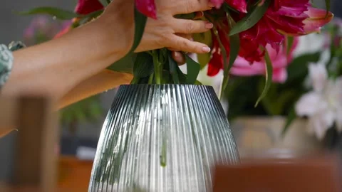 A vase with flowers in it is being filled with water Stock Footage 297775466