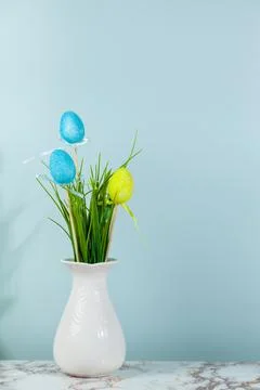 Vase with grass and Easter eggs, space for text, green background. Stock Photos