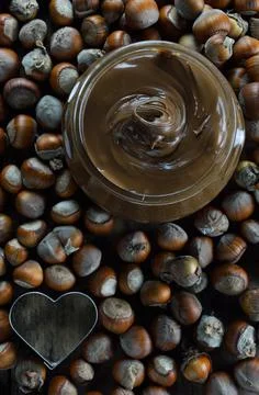 Vase with hazelnut praline paste ,heart shaped cutter and dry hazelnuts Stock Photos