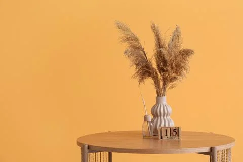 Vase with pampas grass, reed diffuser and cube calendar on coffee table near  Stock Photos