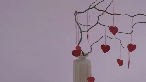 Vase on a pink background with branches and hanging hearts Stock Footage 147627105