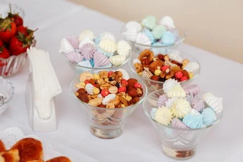 Vases with different sweets on the table, such as meringues, nuts, dried fruits Stock Photos