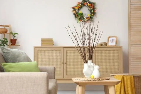 Vases with willow branches and Easter decor on table in living room Stock Photos