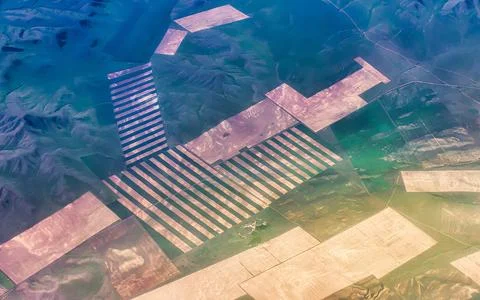 Vast agricultural fields with geometric patterns seen from above in a mount.. Stock Photos