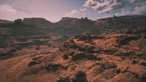 Vast arid landscape with rugged cliffs and clouds in the clear blue sky Stock Illustration