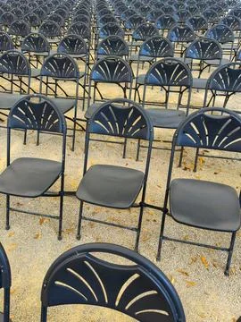 A vast array of empty black chairs arranged in neat rows, awaiting an audienc Foto stock